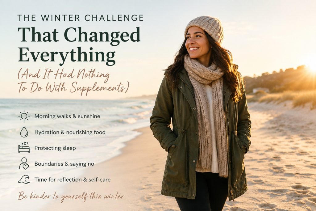 Woman walking along a beach at sunrise during winter, dressed warmly in a coat, scarf and beanie, reflecting on self-care, movement and healthy winter habits.